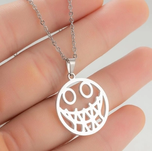 Macro shot of a hand holding a silver stainless steel toothy smiley face pendant necklace