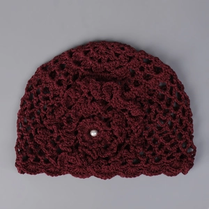 Détail d'un bonnet au crochet bordeaux fait main avec fleur tricotée et perle élégante