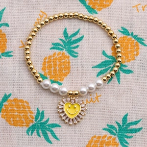 Dettaglio di un braccialetto di perle con perle e un ciondolo a cuore giallo