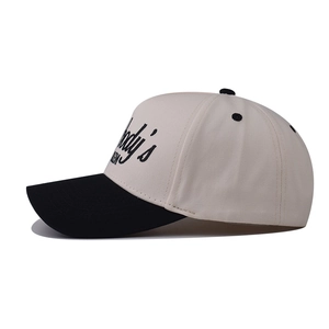 Détail de la broderie noire latérale et texture en coton sur une casquette bicolore