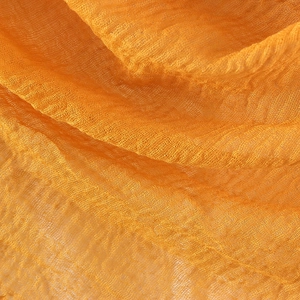 Macro shot of wrinkled golden cotton linen scarf texture showing fine fiber and metallic luster
