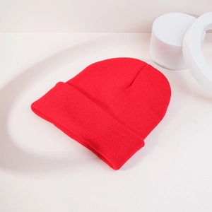 Gros plan du bonnet rouge en tricot côtelé avec revers épais sur un fond blanc minimaliste