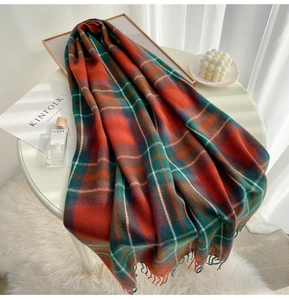 Close-up of red and green plaid scarf with soft fringe edges on a white table