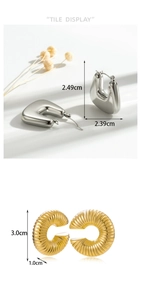 Macro detail of textured gold twisted hoop and polished silver C-shaped metal earrings