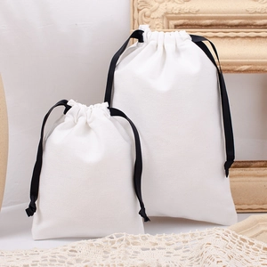 Close-up of two white cotton drawstring bags with black ribbons in different sizes