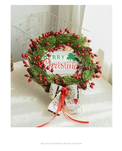 Close-up of Christmas wreath with red berries, burlap base, and Merry Christmas card