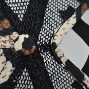 Detailed close-up of breathable black mesh and leopard print fabric on a ponytail cap