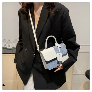 Detail of the white leather and blue denim contrast stitching with a mini fashion tag