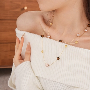 Close-up of double-layer necklace with pink pearls and gold metal beads on a model