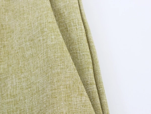 Detailed close-up of light yellow-green linen fabric showing natural woven texture and material