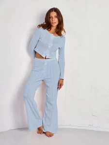 Gros plan sur la maille côtelée bleu clair du cardigan à boutons et du pantalon