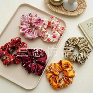 Set of six colorful satin scrunchies featuring floral and polka dot patterns on a tray