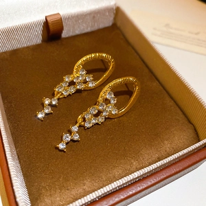 Close-up of gold tassel earrings with clear rhinestones in a brown velvet jewelry box