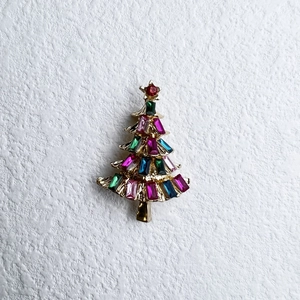 Detailansicht einer Weihnachtsbaum-Brosche mit bunten Strasssteinen und Goldlegierung