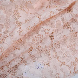 Gros plan sur un tissu en dentelle florale rose clair avec des détails en maille
