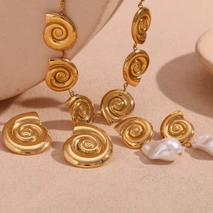 Detail of 18K gold snail shell jewelry set with white baroque pearls on warm sand background