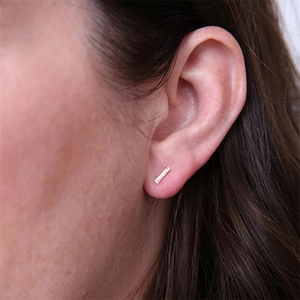 Minimalist gold bar earrings in stainless steel on a model showing the geometric design