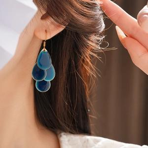 Detail view of tiered deep blue teardrop petal tassels on elegant gold long hook earrings