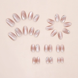 Detailed view of pink cat-eye press-on nails with shiny rhinestones and pearls