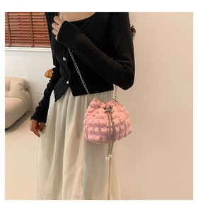 Close-up of pink ruched crossbody bag with metal chain strap and pearl drawstring detail