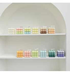 Detailed close-up of colorful bubble cube candles with handmade tags on a minimalist shelf