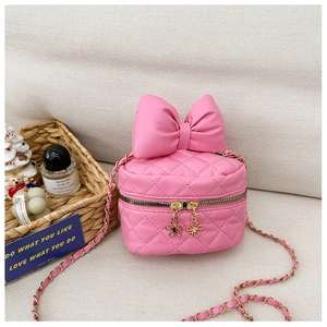 Pink quilted crossbody bag detail with large bow ornament and gold chain strap