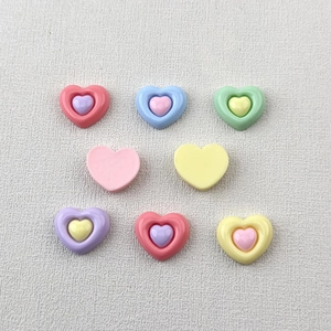 Flat lay of colorful resin heart charms in pink, blue, green, and purple for DIY crafts