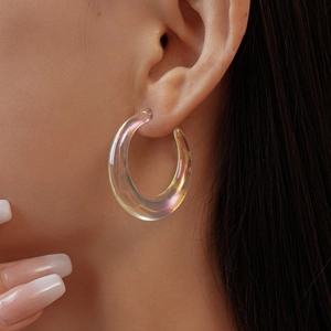 Close-up of a large holographic C-shaped acrylic earring with iridescent finish on model