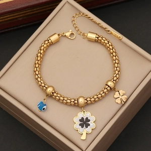 Gold beaded stainless steel bracelet featuring clover charms and a blue evil eye bead
