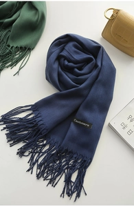 Detail shot of a blue cashmere scarf with fringe tassels and a sewn material label