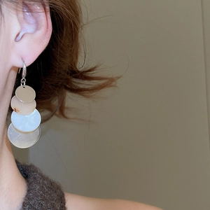 Detail view of stacked acrylic round drop earrings with marble pattern on model