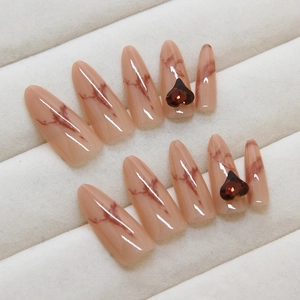 Pink marble press-on nails with deep red heart gems and stiletto shape