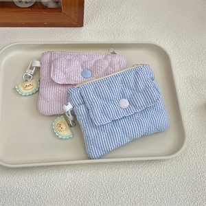 Detailed view of pink and blue quilted coin purses with stripe patterns and charms