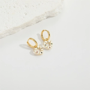 Close-up of heart-shaped gold earring with white oil drop and colorful zircon stones