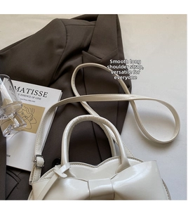 Détail d'un sac à main blanc verni avec nœud élégant et bandoulière à boucle argentée