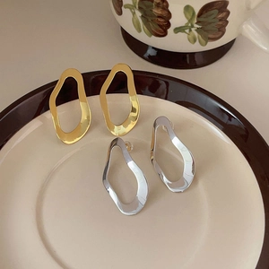 Irregular geometric 925 sterling silver studs in gold and silver finish on a ceramic plate