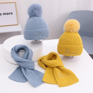 Detailansicht der Kinder-Strickmützen und Schals mit Pompons und Lucky-Bären-Stickerei