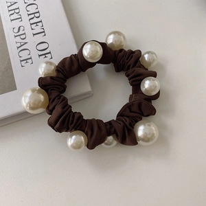 Détail d'un chouchou en tissu marron foncé avec perles et fond de livre décoratif