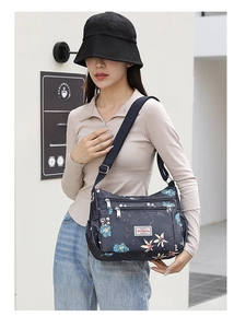 Detailed view of women's floral crossbody bag with multiple zip pockets and strap