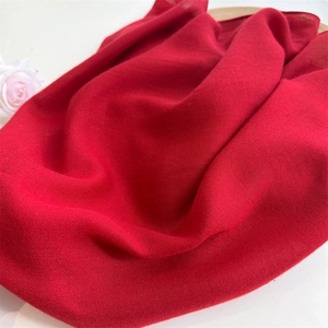 Close-up of red cotton linen fabric with soft natural texture and elegant white rose accent