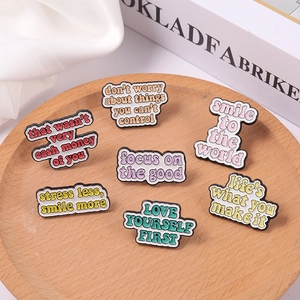 Set of 7 colorful enamel mood pins with positive quotes on a decorative wooden tray