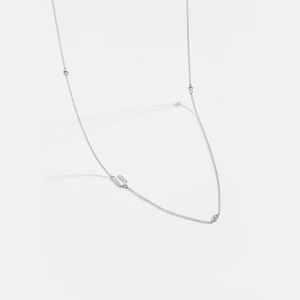 Macro view of silver horseshoe pendant with three inset gems on a delicate chain