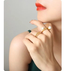 Close-up of stacked gold rings with colorful pearls and zircon stones on a model hand