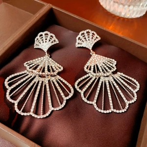Macro detail of silver fan-shaped earrings with layered sparkling crystals in a gift box