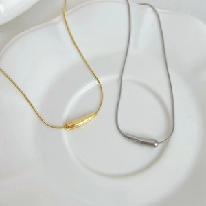 Collane con ciondolo a goccia in oro e argento su un piatto di ceramica bianca