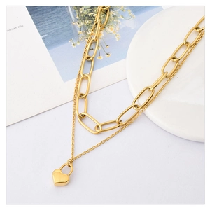 Double layer gold chain necklace with heart lock pendant on a minimalist white setup