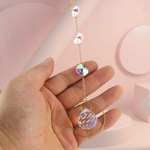 Macro shot of a gold crystal suncatcher pendant held by hand for size reference