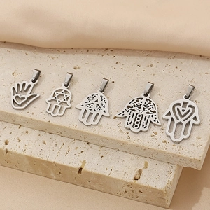 Detail of five silver Hamsa hand charms with intricate cut-outs on a stone stand