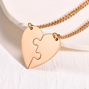 Close-up of rose gold split heart pendant necklaces on a white ceramic plate