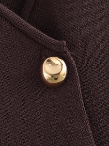 Detailed macro shot of deep brown knit fabric featuring a polished gold metal button